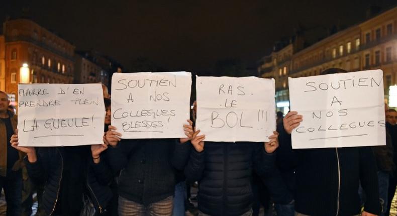 Demonstrators hold placards reading Tired of getting our ass kicked !, Support for our wounded colleagues, Enough ! as they take part in a rally of French police officers in front of the war memorial to protest over mounting attacks on officers