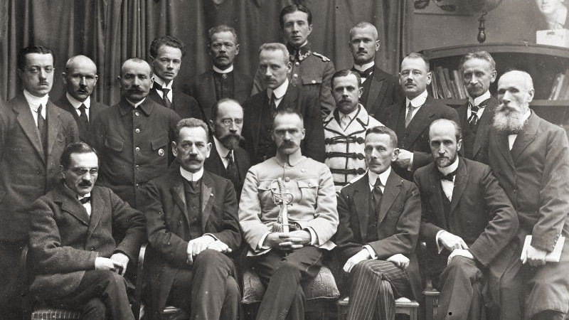 Rząd Jędrzeja Moraczewskiego 18 listopada 1918. W pierwszym rzędzie siedzą (od lewej): Stanisław Thugutt, Jędrzej Moraczewski, Józef Piłsudski, Leon Supiński, Leon Wasilewski - domena publiczna