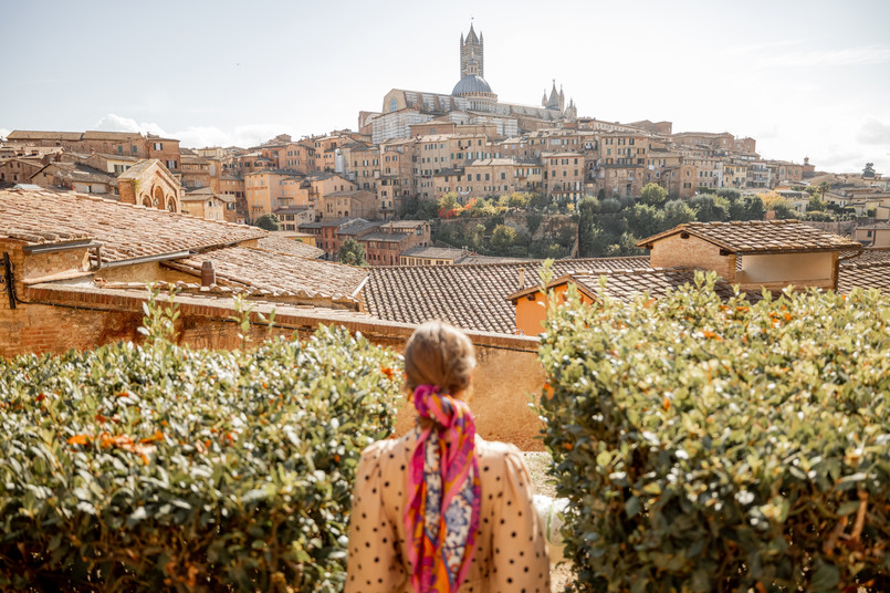 Stylish,Woman,Walks,On,Background,Of,Cityscape,Of,Siena,Old