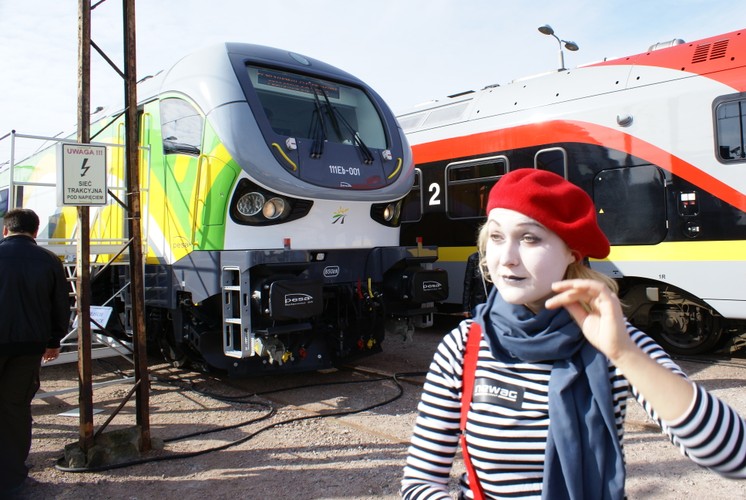 Po lewej stronie widać lokomotywę jedną z dwóch elektrycznych lokomotyw Gama dla Kolei Mazowieckich. Pojazd ma moc 5600 kW i rozwija prędkość maksymalnej 160 km/h. Koleje Mazowieckie to drugi przewoźnik pasażerski, który zdecydował się na Gamą (wcześniej 10 sztuk zamówiła spółka PKP Intercity, ale w wersji spalinowej). Gamy Kolei  Mazowieckich zestawione będą z wagonami piętrowymi.