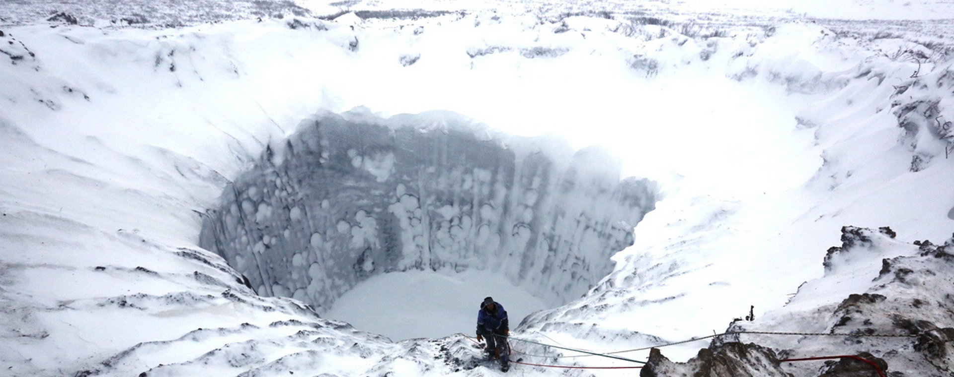 Członek grupy ekspedycyjnej stoi na krawędzi nowo utworzonego krateru na Półwyspie Jamalskim w północnej Syberii