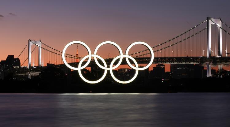 Az olimpiai öt karika kivilágított logója a tokiói Szivárványhíd mellett
