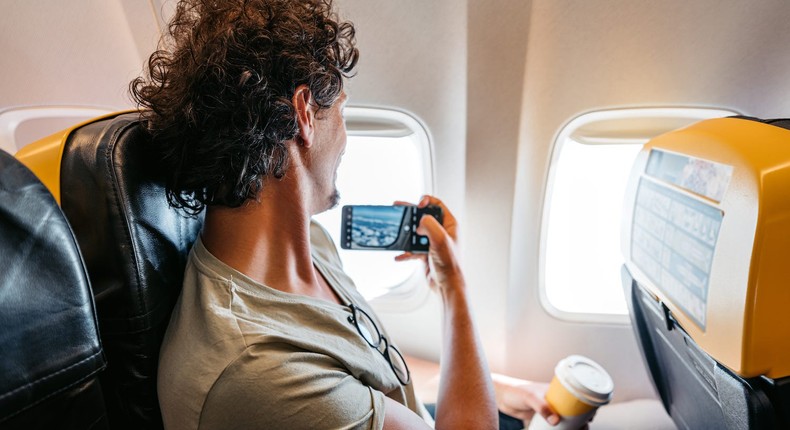 A passenger takes a photo looking out of the plane's window.urbazon/Getty Images