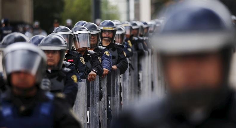 Police officers stand guard as members of the teacher's union CNTE, not pictured, march past the Revolution Monument in Mexico City, June 1, 2015.