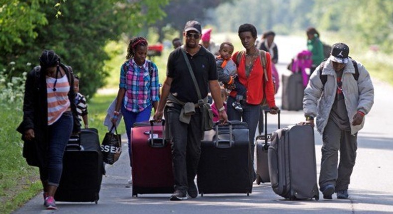 Asylum seekers walk down Roxham Road to cross into Quebec at the U.S.-Canada border in 2017