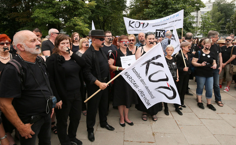 Protestujący przed Sejmem zakleili sobie usta czarną taśmą. Mieli ze sobą biało-czerwone chorągiewki, czarne kartki z napisem "TK" i transparenty.