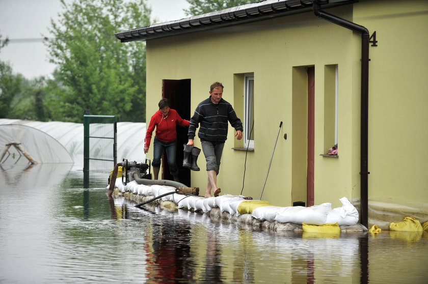 Ludzie na grobli z worków z piaskiem wychodzą z żółtego domu