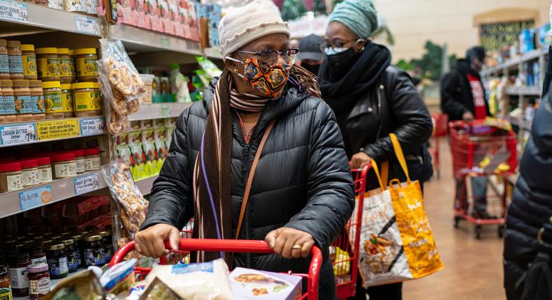 A woman wearing a mask moves her shopping cart inside a supermarket
