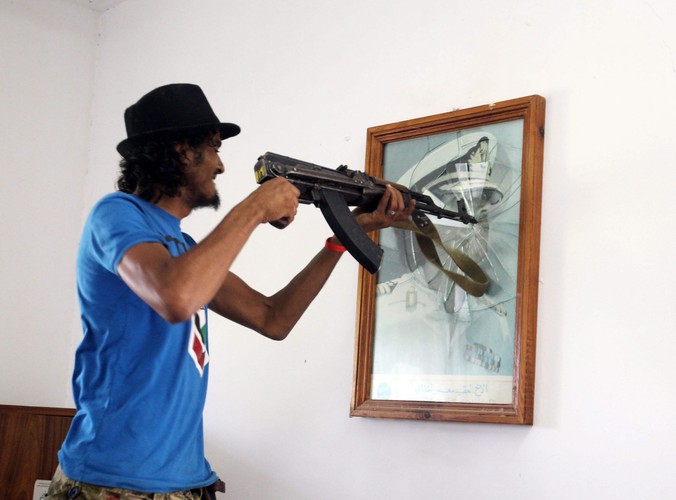 Jeden z powstańców niszczy portret Kaddafiego w szpitalu w Syrcie