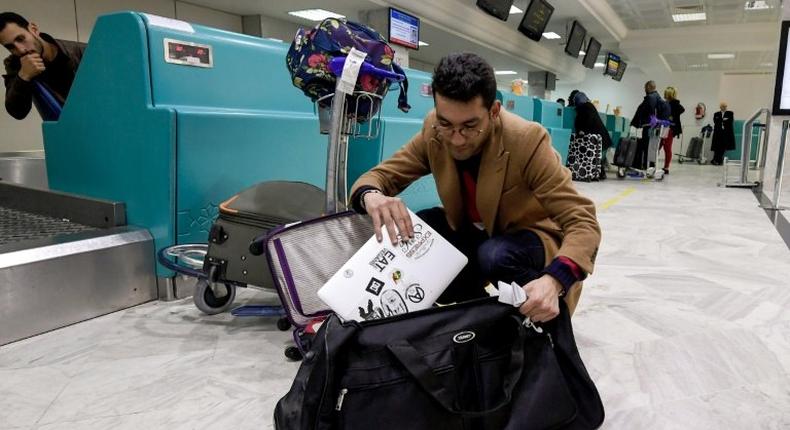 A Libyan traveller packs his laptop in his suitcase before boarding his flight for London at Tunis-Carthage International Airport on March 25, 2017