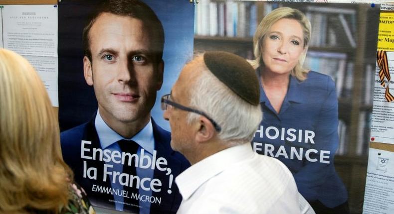 A French citizen walks past election posters of French presidential candidates Emmanuel Macron and Marine Le Pen before casting his vote at the French consulate in Tel Aviv on May 7, 2017