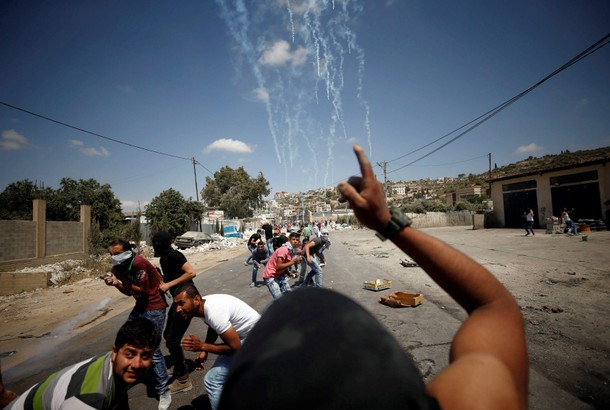 Palestinian protesters take cover during clashes with Israeli troops in the West Bank village of Bei