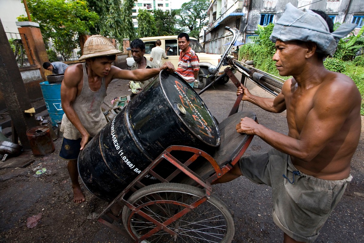 Robotnicy transportują baryłkę ropy naftowej na czarnorynkowym straganie w Yangon w Birmie.
