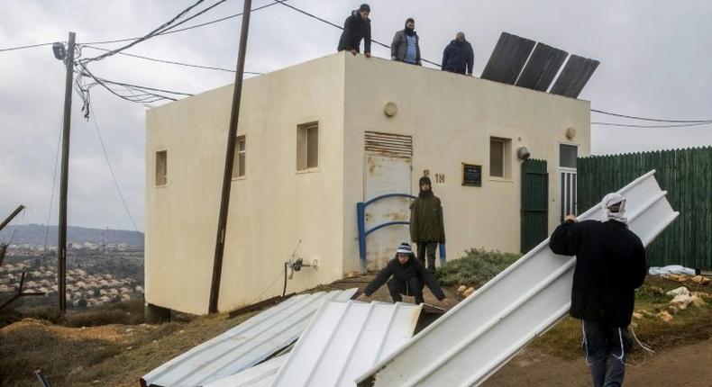 Israeli settlers block the entrance to the the settlement outpost of Amona, in the Israeli-occupied West Bank