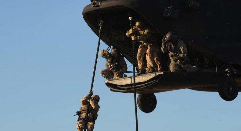 Navy SEALs fast rope during a training evolution.