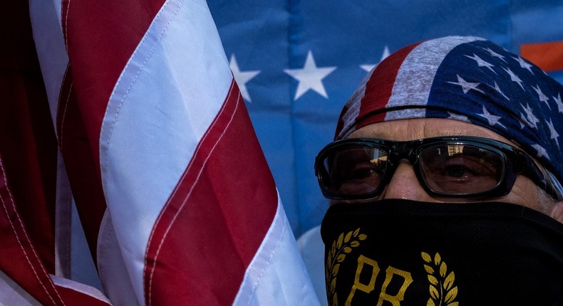 A member of the Proud Boys holds an US national flag during a rally against gender-affirming care by Vanderbilt University Medical Center, at the War Memorial Plaza in Nashville, Tennessee, on October 21, 2022.Photo by SETH HERALD/AFP via Getty Images