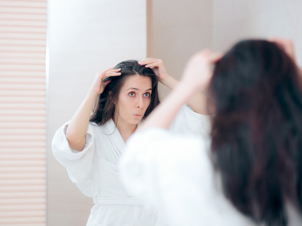 Kobieta ogląda swoje włosy w lustrze