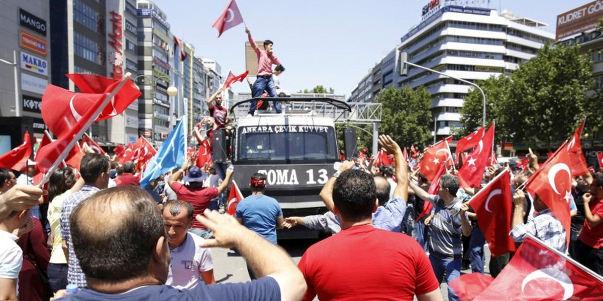 A supporter of Turkish President Recep Tayyip Erdogan celebrates with a flag on top of a police car in Ankara.
