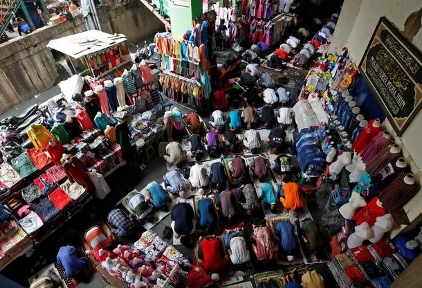 Muslim labourers and shop keepers attend Friday prayers on a street next to Tanah Abang Textile Mark