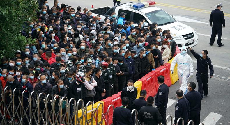 Airport staff wait for COVID-19 tests at a parking lot at the Shanghai Pudong International Airport on November 23, 2020.