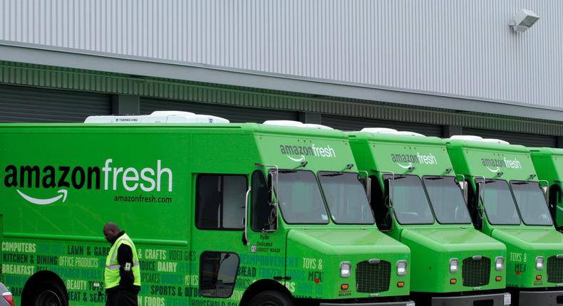 A worker walks past Amazon Fresh delivery vans parked at an Amazon Fresh warehouse in Inglewood, California.