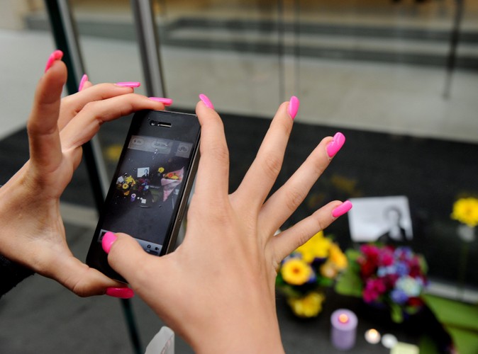 Kobieta fotografuje swym iPhonem kwiaty złożone na George Street w Sydney