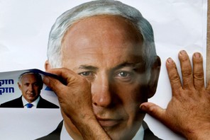 FILE PHOTO: A Likud party supporter puts up a poster depicting party leader Benjamin Netanyahu in th