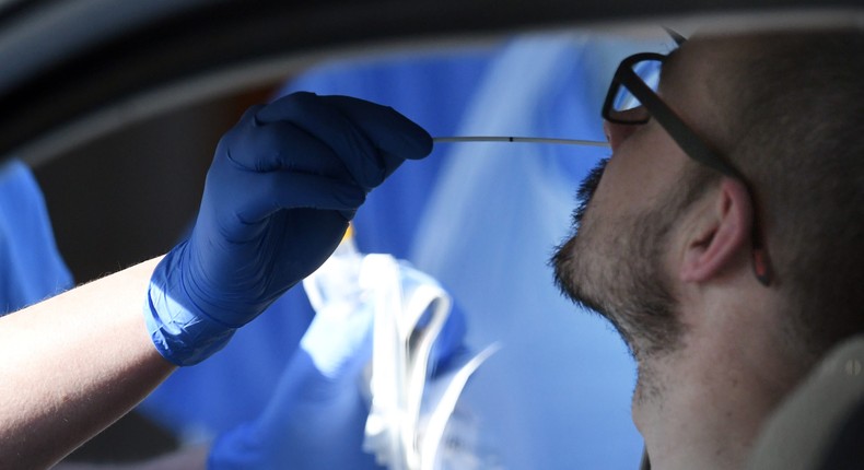 A medical staff member wearing PPE of gloves, eye protection, a face mask and an apron, tests an NHS worker for the novel coronavirus COVID-19 in Wolverhampton, central England on April 07, 2020.
