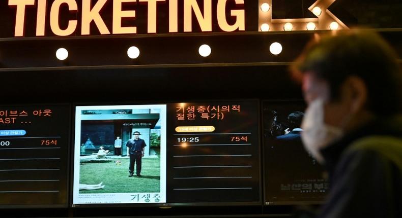 A man walks past a screen showing a poster of Bong Joon-ho's film 'Parasite' at a cinema in Seoul on the day the movie won the Oscar for best picture