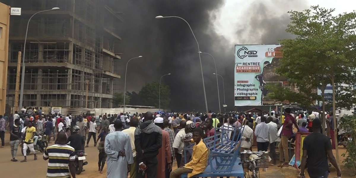 Demonstracja w Niamey, stolicy Nigeru, czwartek, 27 lipca 2023 r. W tle płonie siedziba partii rządzącej