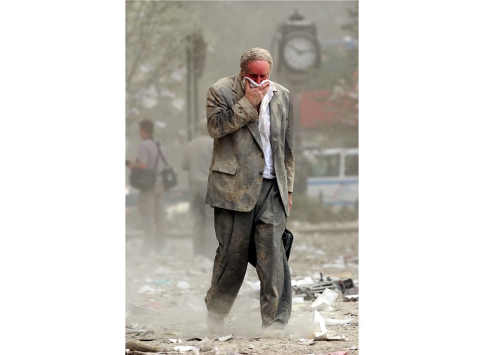 Mężczyzna osłania twarz przed pyłem powstałym w wyniku zawalenia się nowojorskich wież World Trade Center