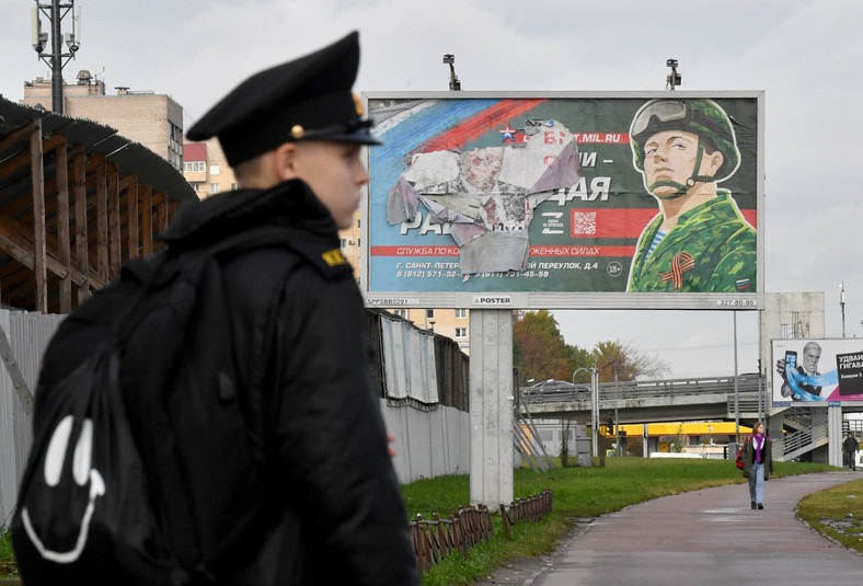 Kadet wojskowy przed billboardem promującym służbę kontraktową w Sankt Petersburgu, Rosja, 5 października 2022 r.