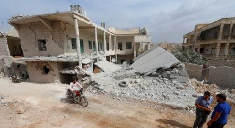 A man drives a motorcycle near a site hit by what residents said were airstrikes carried out by the Russian air force in the town of Darat Izza, in Aleppo province, Syria October 13, 2015.