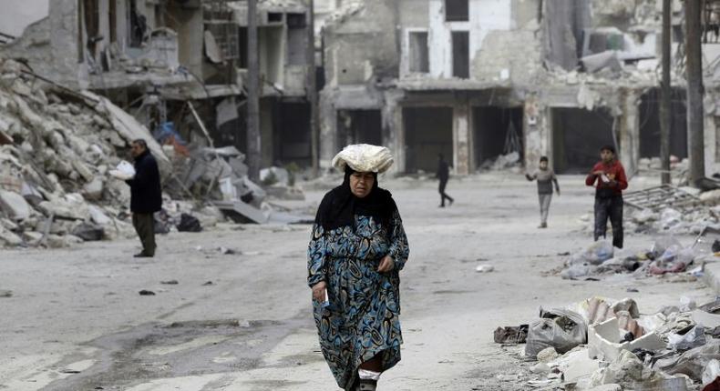 A woman walks up a street lined with heavily-damaged buildings in former rebel-held district of Shaar that Syrian government forces recaptured in December, in picture taken on March 9