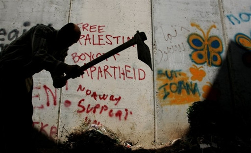 Palestinian man works on his land which faces Israel's separation wall in the West Bank village of Nazlat Issa, on September 27, 2010. This section of Israel's controversial barrier was built in 2003.