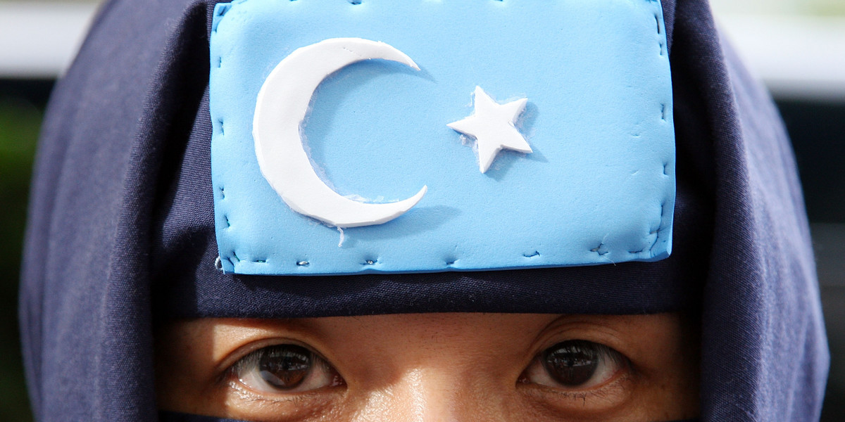 An activist protests while wearing the Uighurs' flag.
