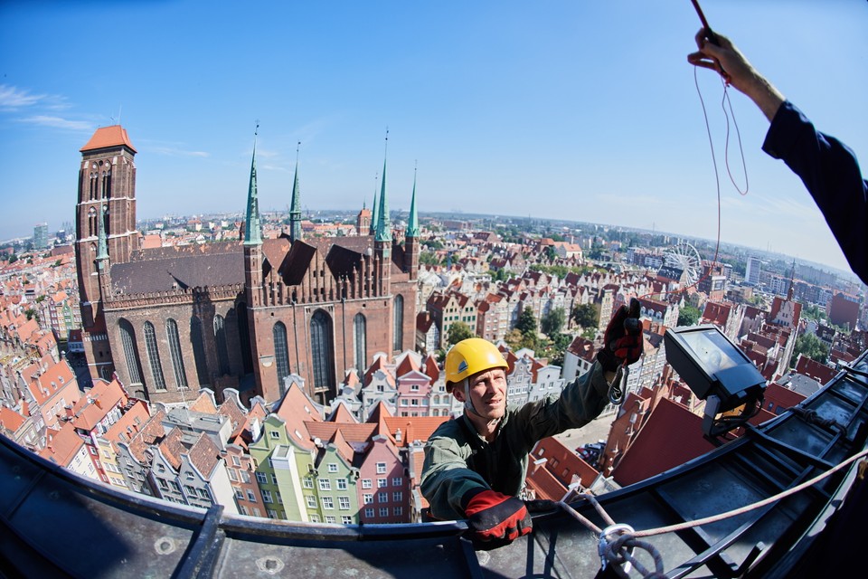 Alpinista dokonuje oględzin mechanizmów zegara Ratusza Głównego Miasta w Gdańsku