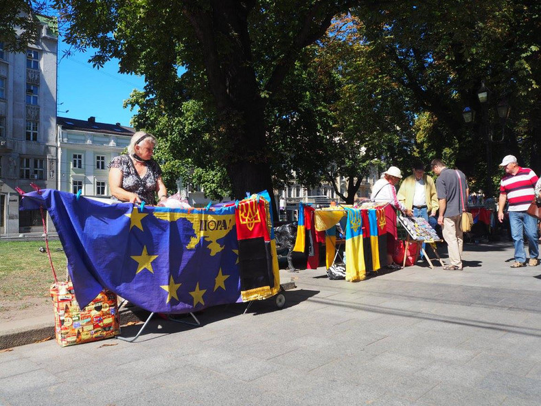 Ukraińskie, i czerwono-czarne flagi mieszają się z flagami Unii Europejskiej Targowisko z pamiątkami w centrum Lwowa