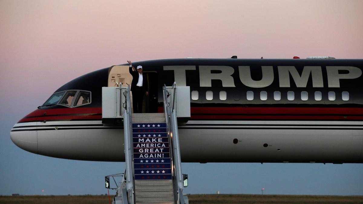 Republican presidential nominee Donald Trump waves as he walks off his plane at a campaign rally in 