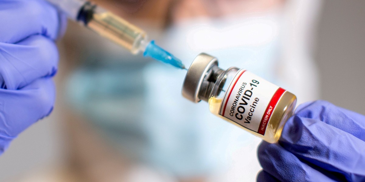 FILE PHOTO: A woman holds a medical syringe and a small bottle labeled "Coronavirus COVID-19 Vaccine