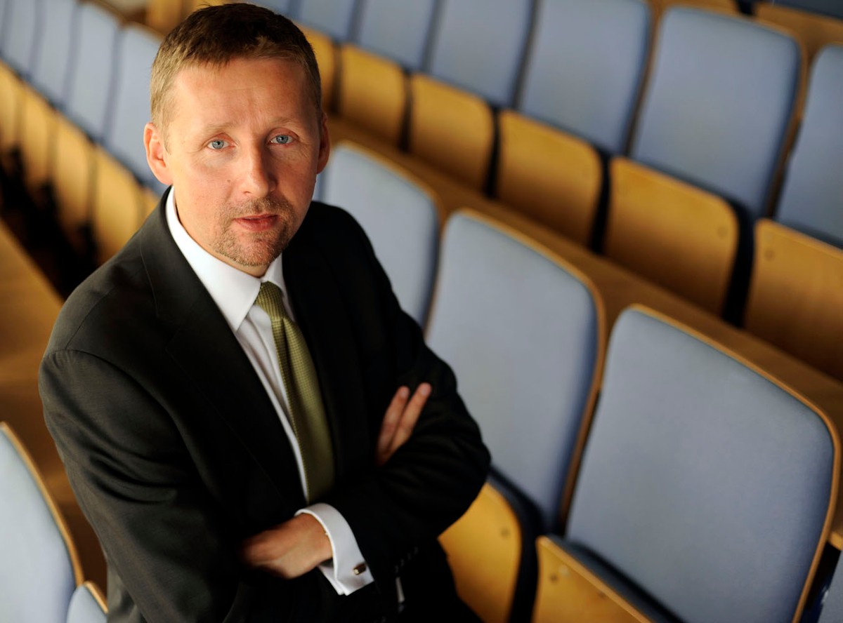Polityk Marek Migalski stoi z założonymi rękami w uniwersyteckiej auli