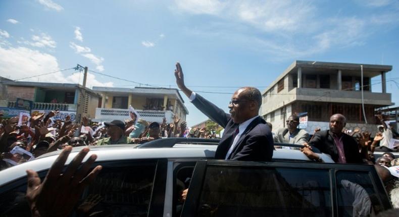 Former Haitian president Jean-Bertrand Aristide greets supporters in Port-au-Prince in a rare public outing to testify in a money laundering case