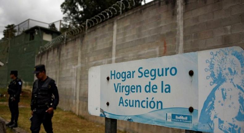 Police agents stand guard next to a sign that reads Sage home Virgen de la Asuncion at the children's shelter entrance after 40 girls died during a fire on March 8, in San Jose Pinula, on March 15, 2017