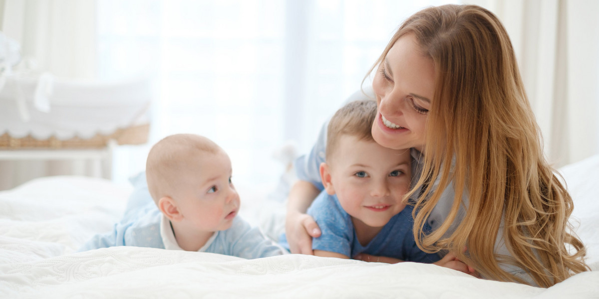 Happy middle aged mother with her children in a bed