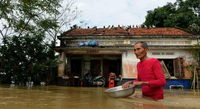 A man wades through floodwaters in front of his home in the central Vietnamese province of Binh Dinh on December 18, 2016