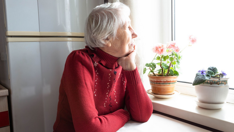 Starsza kobieta siedzi przy oknie