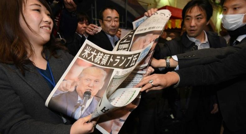 A woman in Tokyo gives out extra editions of a newpaper reporting the victory of Donald Trump in the US presidential election