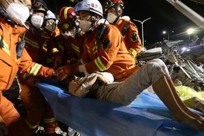 Rescue workers wearing face masks move a boy from the rubble of a collapsed hotel which has been used for medical observation following an outbreak of the novel coronavirus, in the southeast Chinese port city of Quanzhou, Fujian