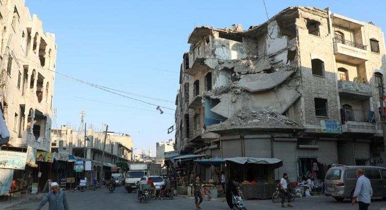 People walk near heavily damaged buildings in the rebel-held city of Idlib in northwestern Syria on September 16, 2019