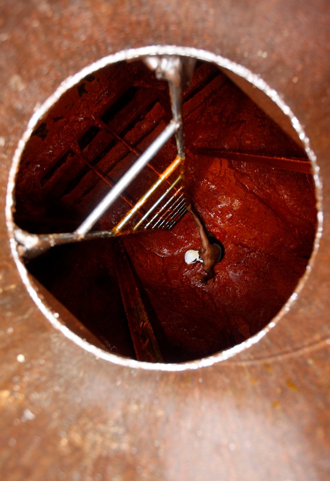 A worker cleans crude palm oil inside a container at Tanjung Priok port in Jakarta